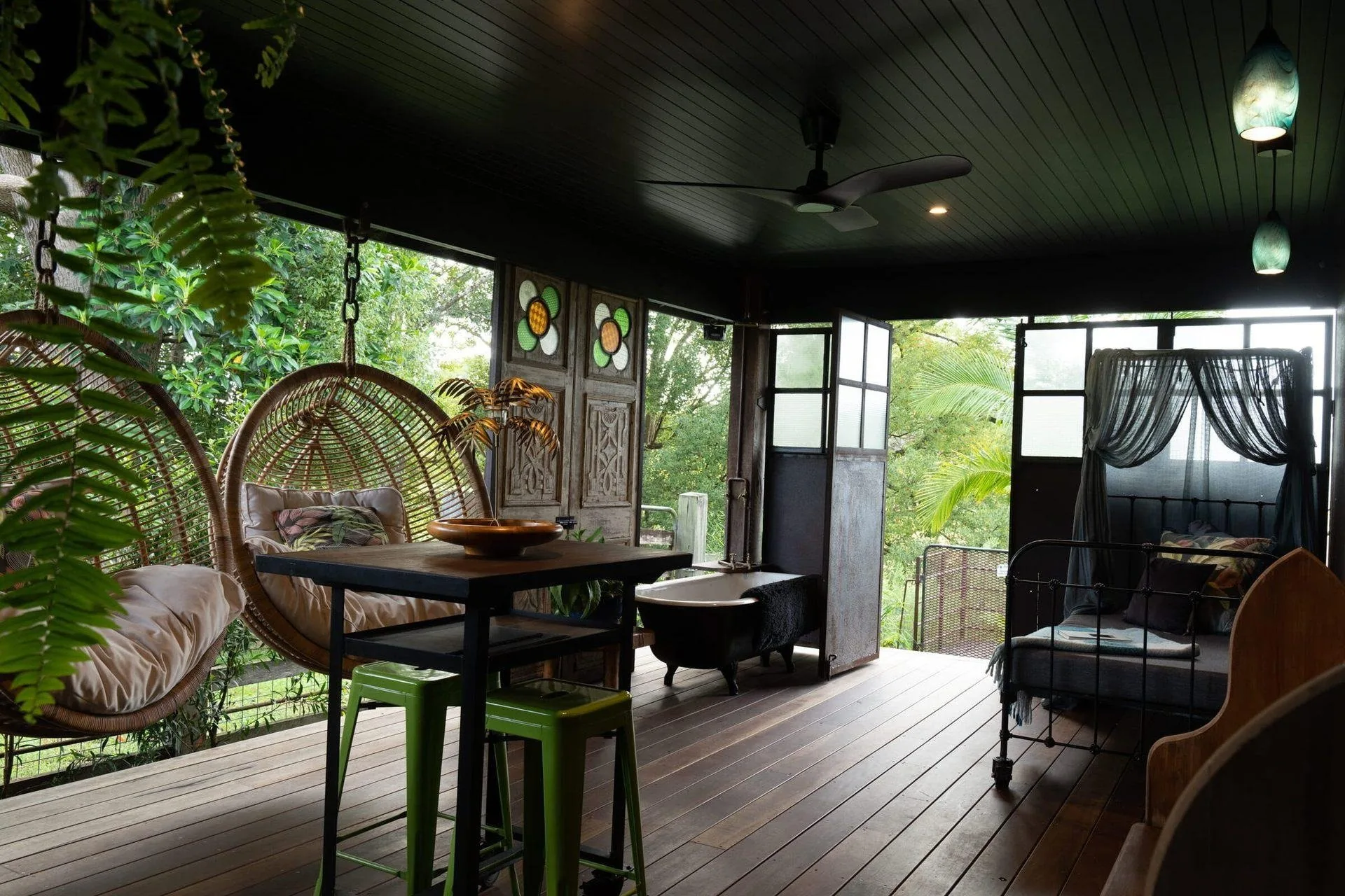 The Barnita covered deck with hanging chairs, a daybed and an antique bathtub